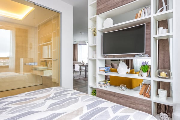 Spacious living room with multiple upholstered sofas, large windows with blue shutters, potted plants, and polished concrete flooring.