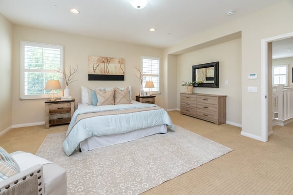 Spacious living room with multiple upholstered seating areas, large windows with shutters, potted plants, and polished concrete flooring