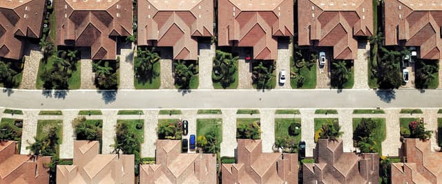 Aerial top-down view of a Florida residential neighborhood with terracotta rooftops, palm trees, and screened pools