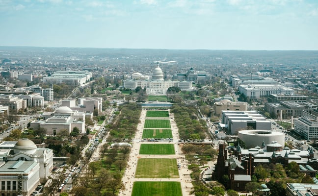 Aerial view of the National Mall in Washington DC with the US Capitol building, green lawns, and Smithsonian museums on a clear spring day