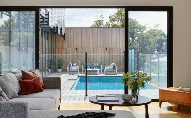 Stone patio with hanging swing chair overlooking tree-lined driveway and rolling countryside landscape
